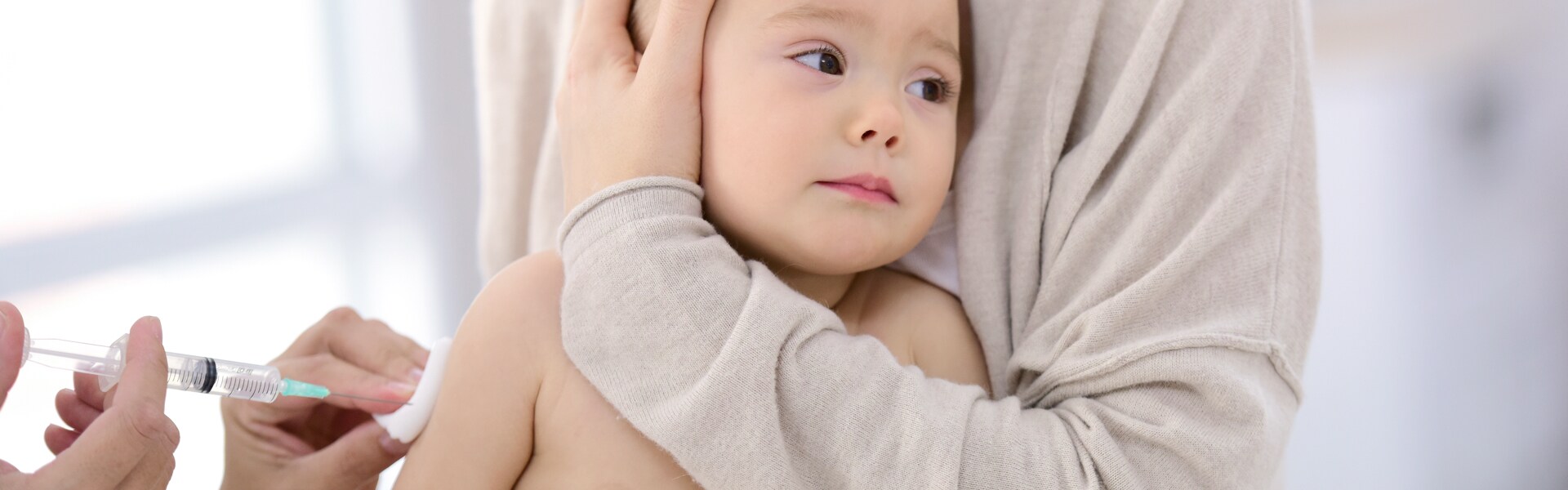 Mutter hält ihr Baby, während es geimpft wird