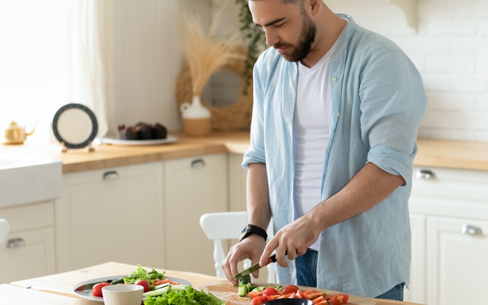 Junger Mann kocht gesundes Essen