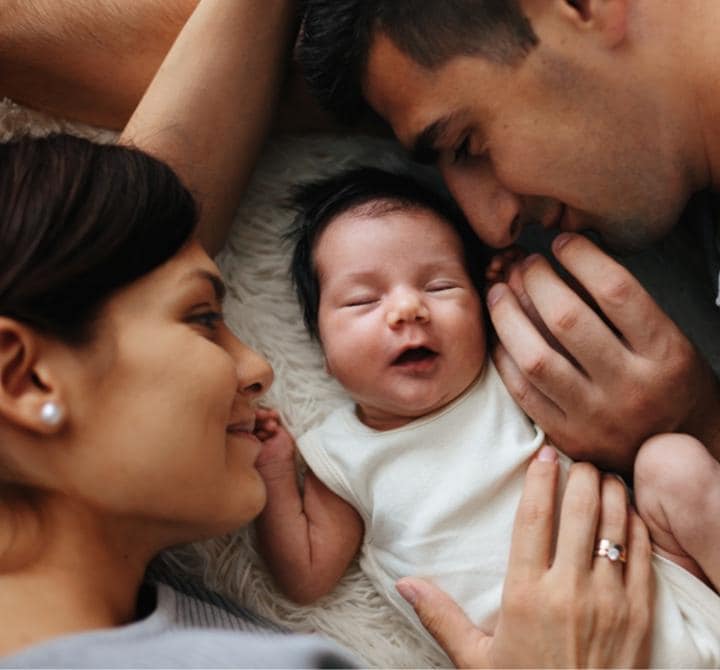 Das lächelnde Paar sieht das Baby an