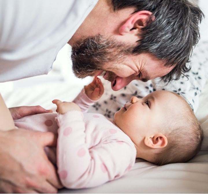 Vater lächelt und umarmt das lügende Baby