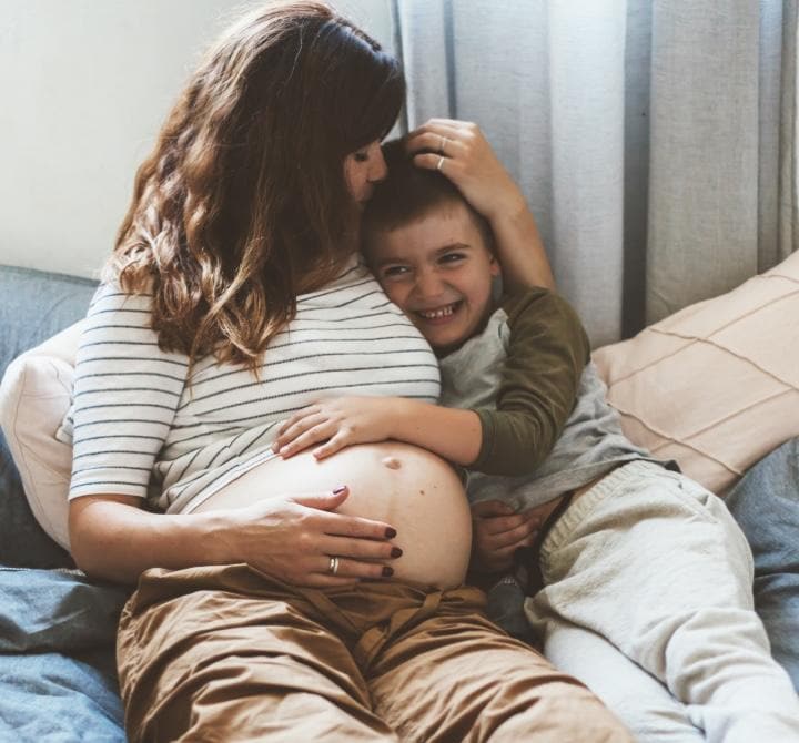Das Baby kuschelt sich an die schwangere Mutter